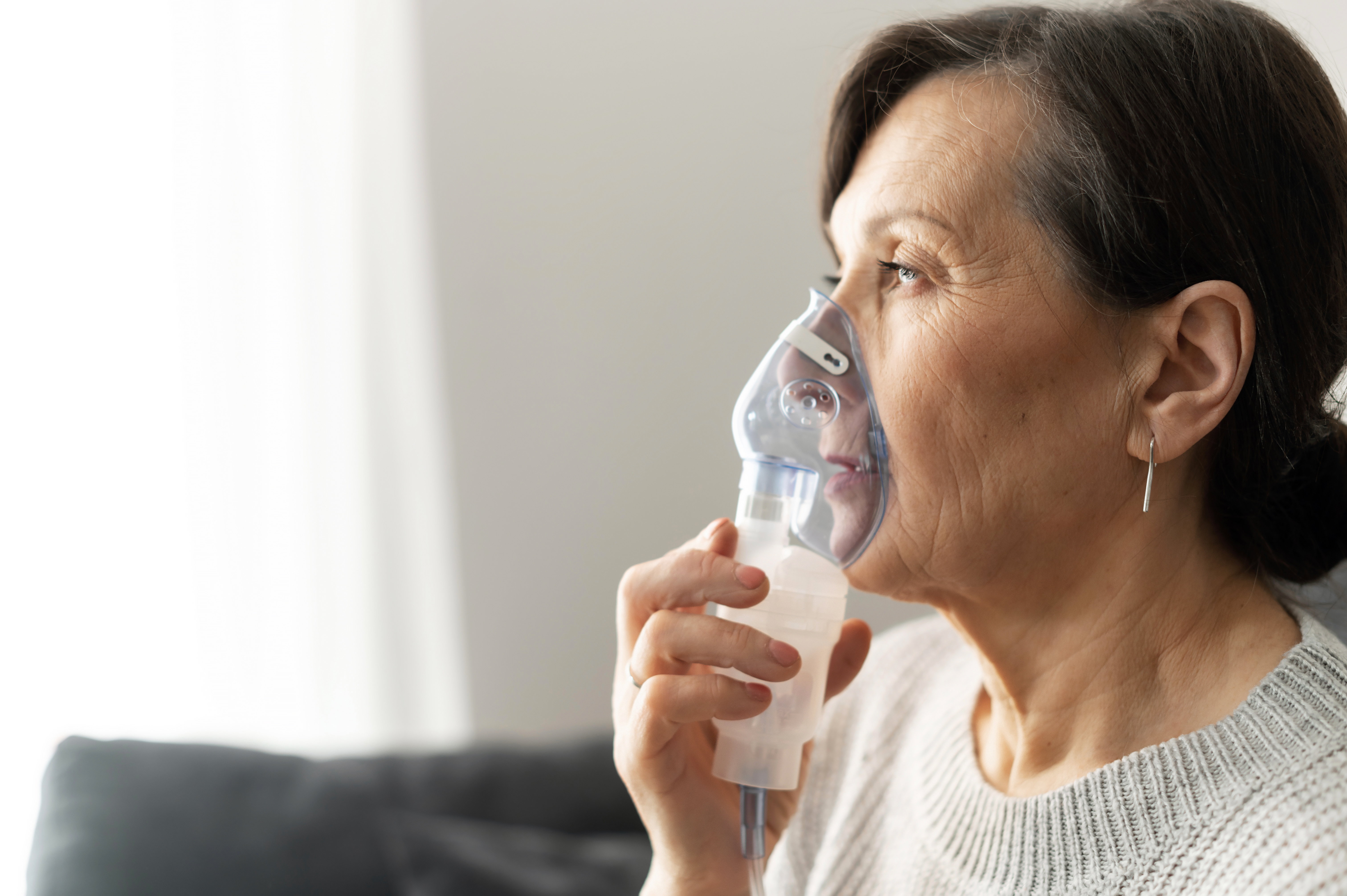 elderly woman receiving a breathing treatment using a nebulizer machine