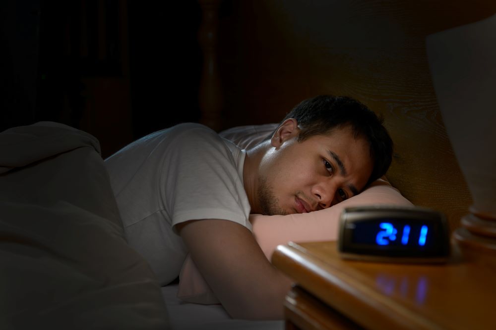Man having trouble sleeping at 2:11 am while in his bed